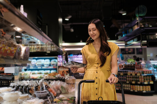 Young Asian woman buying convenience food in supermarket