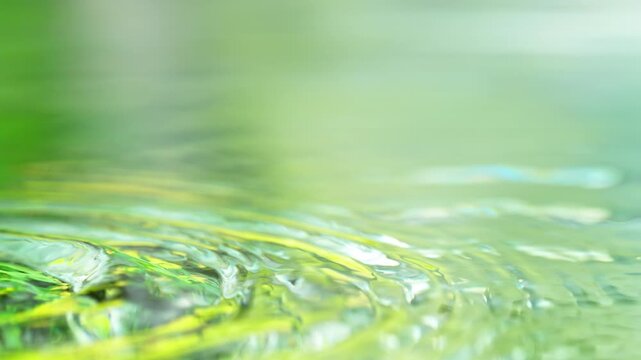 Super Slow Motion Shot of Rippling Water Surface with Fresh Green Background at 1000fps.