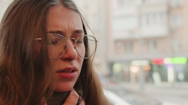 Closeup of woman crying in city scene. Woman wiping tears with trembling hands in urban setting. Raw emotional release captured as distressed woman mourns in bustling city background