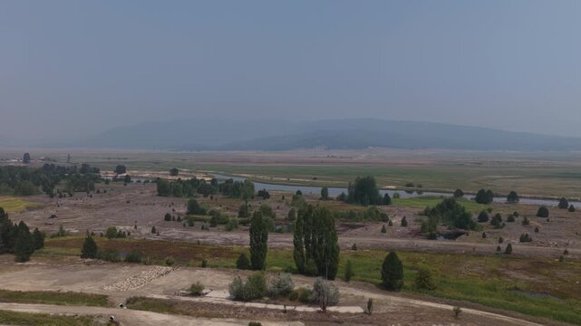 Aerial of North Fork Payette River valley wetlands and grasslands in Cascade Idaho in smoky skies in summer