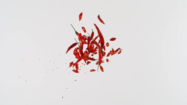 Super Slow Motion Shot of Flying Chilli Peppers Pieces Isolated on White Background at 1000fps.