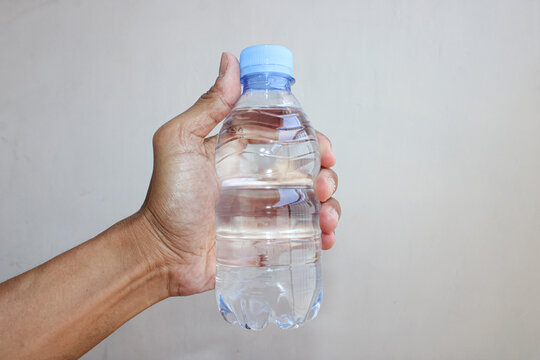 Hand Holding Fresh Mineral Water Plastic Bottle Isolated On Background