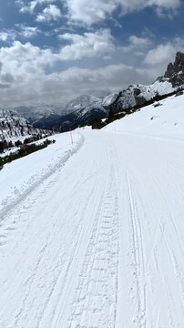 Point of view skiing downhill with friend snowboarding in dolomites