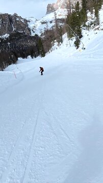 Snowboarder gliding down a snowy mountain slope in the dolomites