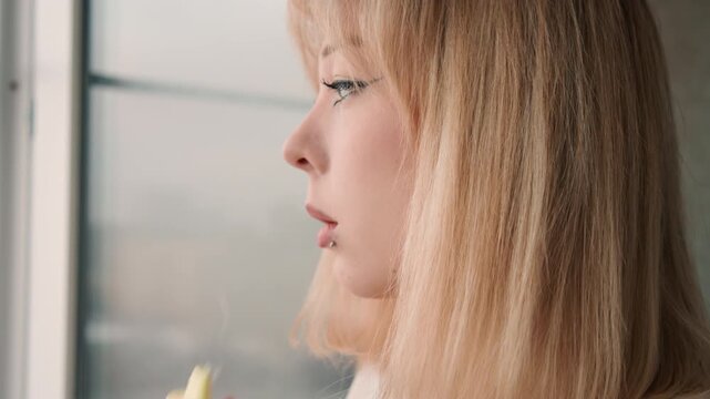 Blonde caucasian woman closeup profile tasting. Cinematic mood ASMR vibe, chef persona sampling ingredient, creator testing flavor, reflective pause by urban window, soft natural light, minimal