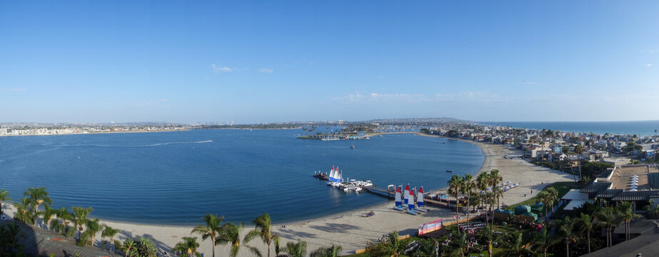 Aerial view of Sail and Mission Bays and Pacific ocean showing the beach, small sailboats, palm trees and numerous vacation and hotels properties, Southern California