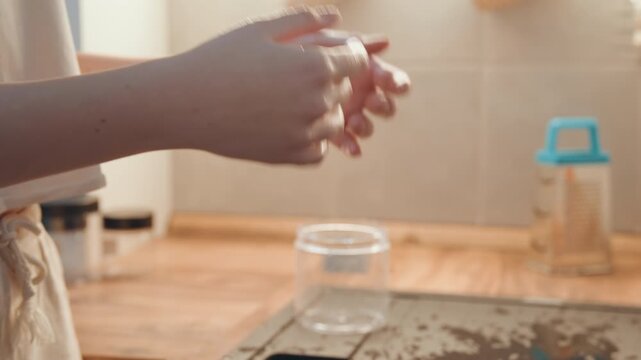 Hands drying and setting empty jar on wooden counter by sink meal prepper catches droplets with fingertips, calm sunlight, final tidy motion completes ingredient prep in cozy kitchen