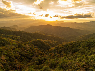 Obraz premium Dramatic sunset over mountain landscape. Dawn sky gold dusk time cloudscape with sunlight. Blue golden sky sunrise dramatic beautiful landscape mountain. Beautiful landscape foggy hills twilight time