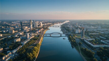 Fototapeta premium Aerial View of a Cityscape with River and Bridges Under Clear Sky at Sunset