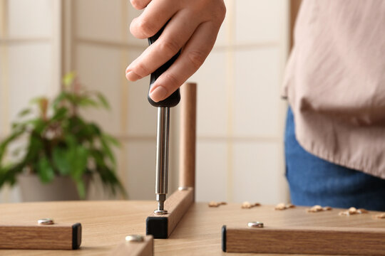 Person assembling furniture with a screwdriver, home improvement and diy concept, close up of hands and tools