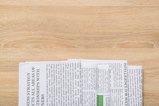 Newspaper with lorem ipsum text on a light wooden table, business and communication concept, top view with copy space