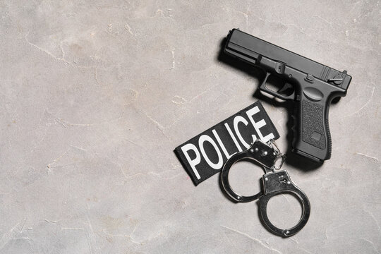 Black pistol, police patch, and metal handcuffs on a gray concrete background, law enforcement and justice
