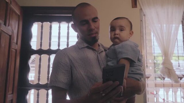 Father holding his infant son during video call