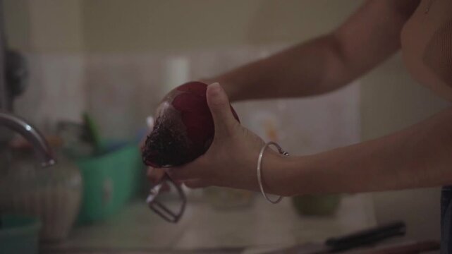Close up of a person peeling a beetroot in a kitchen