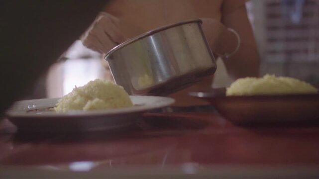 Person serving cooked rice on a plate
