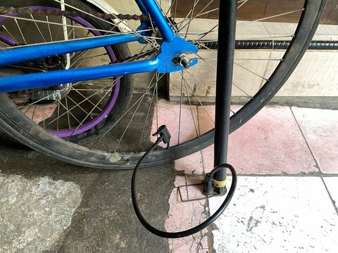 A bicycle is being inflated using a manual tire pump for maintenance and repair purposes.