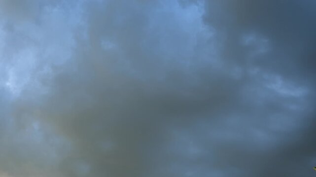 Timelapse of late day grey to orange clouds filling the frame and drifting across a blue sky