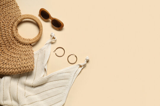 Female summer dress with beach bag, sunglasses and earrings on beige background