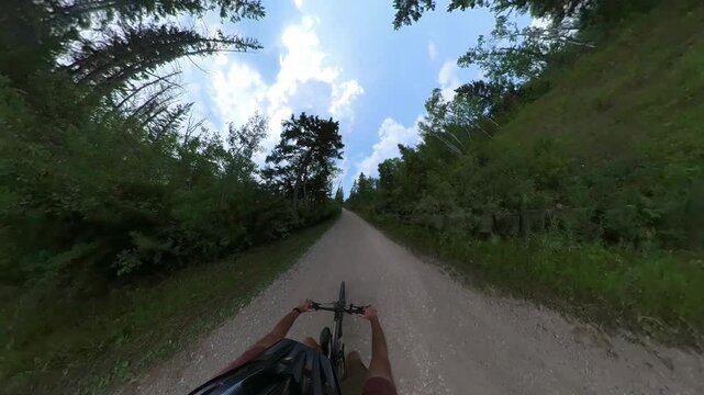 Extreme wide-angle from a cyclist as he is riding along a narrow trail trough an evergreen forest
