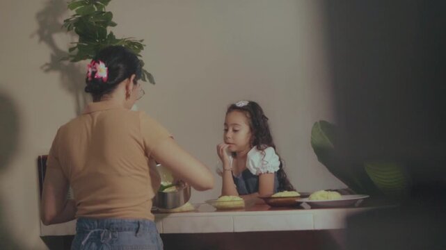 Hispanic mother serving dinner to her daughter