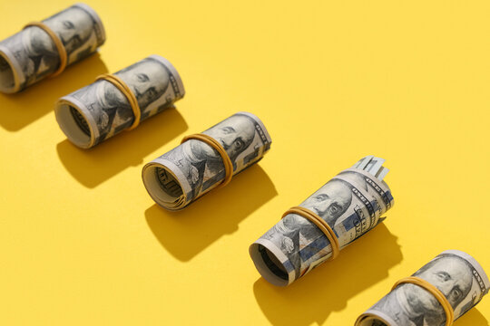 Rolled dollar banknotes on yellow background