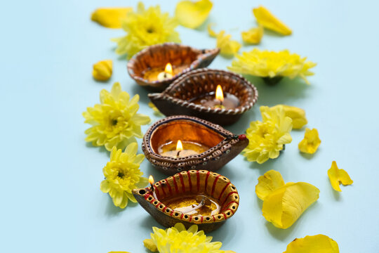 Diya lamps with flowers on blue background. Divaly celebration