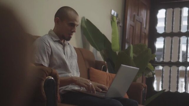 Focused hispanic man typing on laptop computer