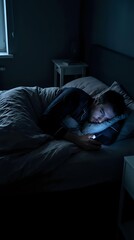 Fototapeta premium Man lying in bed at night scrolling smartphone, screen glow illuminating face in dark bedroom, depicting insomnia and late night phone addiction.