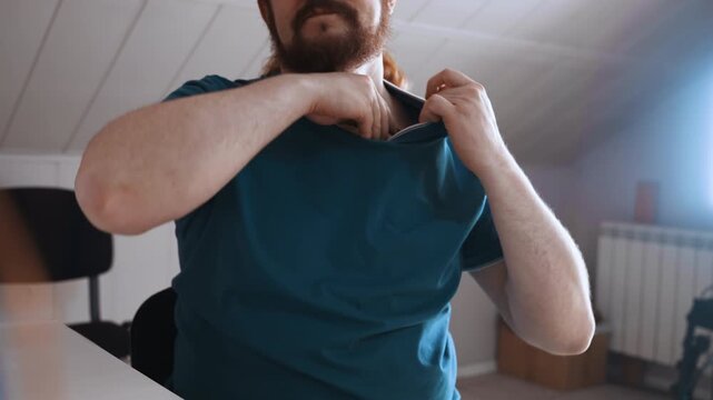 White male patient checking injection site after treatment, rubbing shoulder and adjusting shirt, subtle discomfort and careful observation, indoor attic room with natural light, focused self