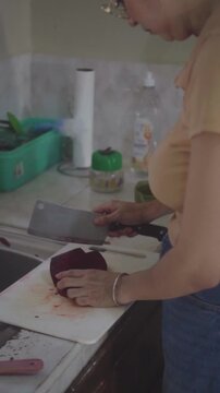 Woman cutting fresh red beetroot with a cleaver