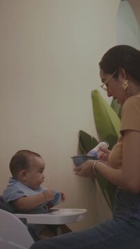 Mother feeding her infant son with spoon
