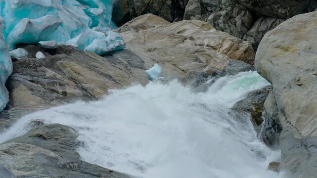 Static shots of a powerful glacial meltwater river flowing from Nigardsbreen Glacier in Norway. Turquoise fragments of ice lie among the rocks as rapidly flowing water rushes through the rugged glacia