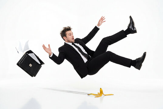 Clumsy businessman falling backwards after slipping on a banana peel