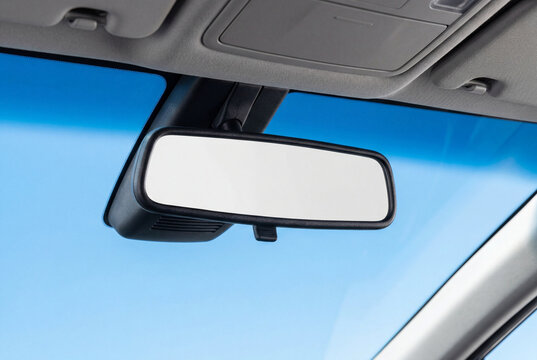 Blank rearview mirror inside modern car against clear blue sky