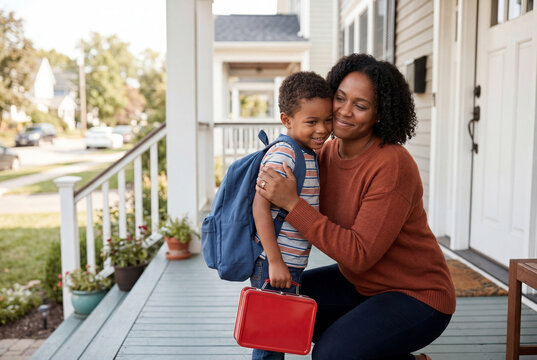 African american mother hugging son before school on front porch