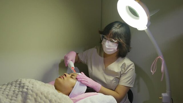 Beautician performing high frequency facial treatment in a spa