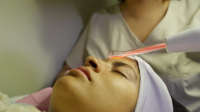 Woman receiving darsonval facial treatment therapy