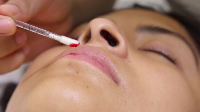 Cosmetologist applying permanent makeup to a woman's lips