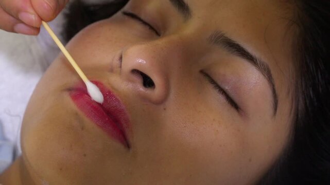 Cosmetologist applying permanent makeup lip treatment