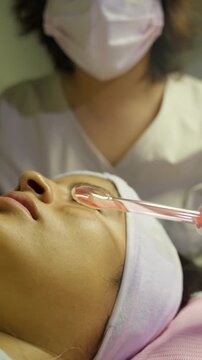 Esthetician performing high frequency facial treatment on client