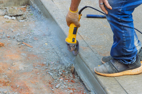 Worker cuts concrete with grinder during construction at worksite