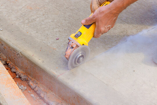 Worker uses cutting tool on concrete surface at construction site