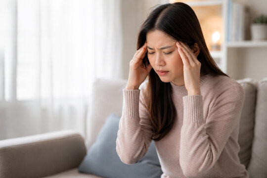 AI generated woman migraine headache pressing temples at home showing pain stress fatigue discomfort ideal for healthcare wellness medical advertising