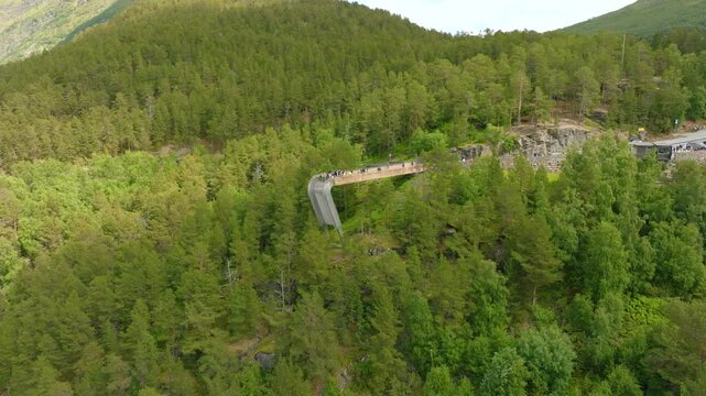 Aerial drone footage of Stegastein viewpoint in Aurland, Norway, surrounded by steep forested mountains and the scenic Aurlandsfjord landscape.