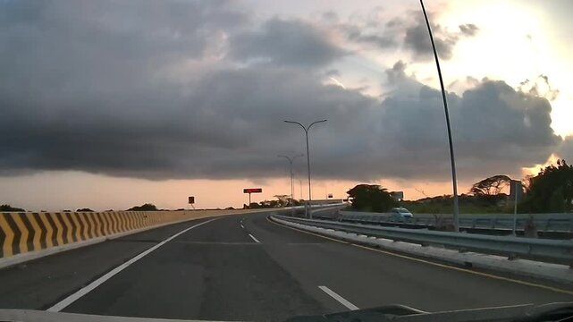 Front Dashcam Driving on Curved Approach Road to Juanda Toll Gate Under Dramatic Morning Sky in Indonesia
