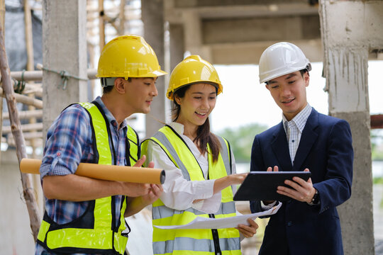 Architects, engineers and a manager discussing blueprints during a site inspection.