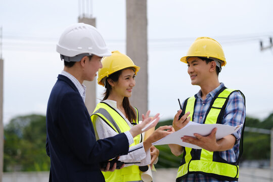 Architects, engineers and a manager discussing blueprints during a site inspection.