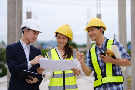 Architects, engineers and a manager discussing blueprints during a site inspection.