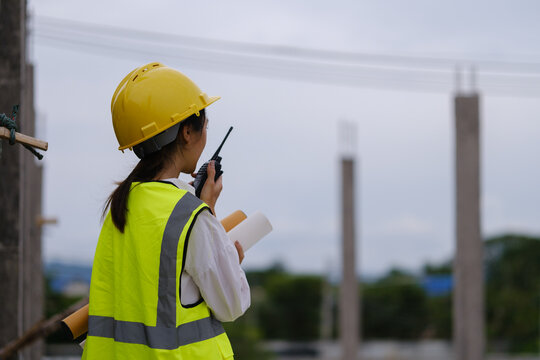 Construction professionals using a two-way radio during a building site inspection.
