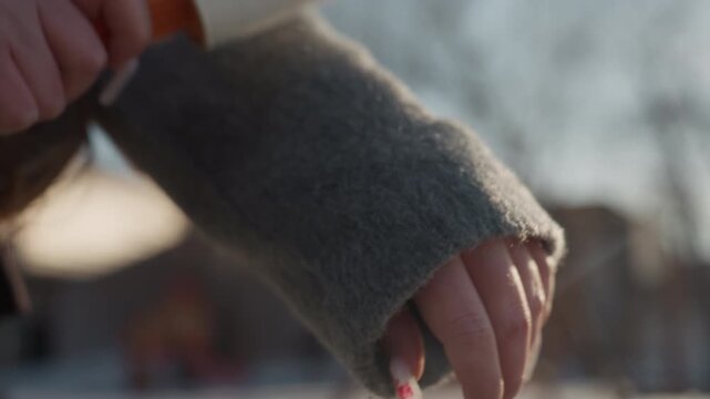 Cleaning wool with lint roller. Closeup of lint roller brushing fuzz from warm sweater outdoors. Detailed image of hand using lint roller to tidy fuzzy wool clothing in natural sunlight